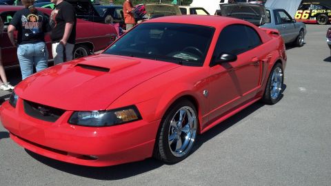 2007 Ford Mustang - A red 2007 Ford Mustang is parked at an outdoor car show with other vehicles visible.