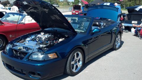2007 Ford Mustang - A dark blue convertible Mustang is displayed with its hood open, revealing the engine compartment. Other vehicles are parked nearby.