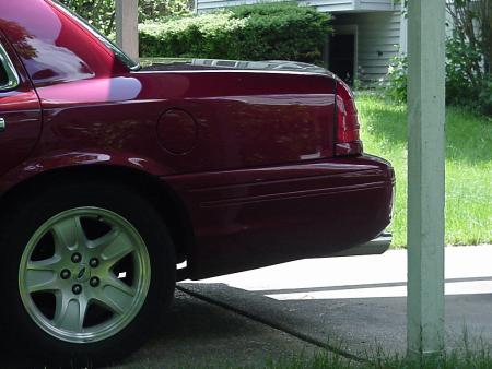 2002 Ford Crown Victoria - The rear of a maroon 2002 Ford Crown Victoria is visible, parked under a carport.
