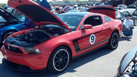 2007 Ford Mustang - A red Ford Mustang with racing stripes and the number 9 is displayed at a car show with its hood open.