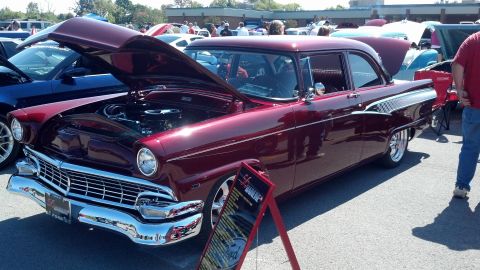 2007 Ford Mustang - A maroon 1956 Ford sedan is displayed with its hood open at a car show, alongside other vehicles.