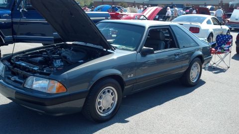 2007 Ford Mustang - A gray Ford Mustang with its hood up is parked at an outdoor car show. The 5.0 badge is visible on the fender.