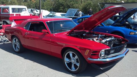 2007 Ford Mustang - Classic red Ford Mustang displayed at a car show with other vehicles present.