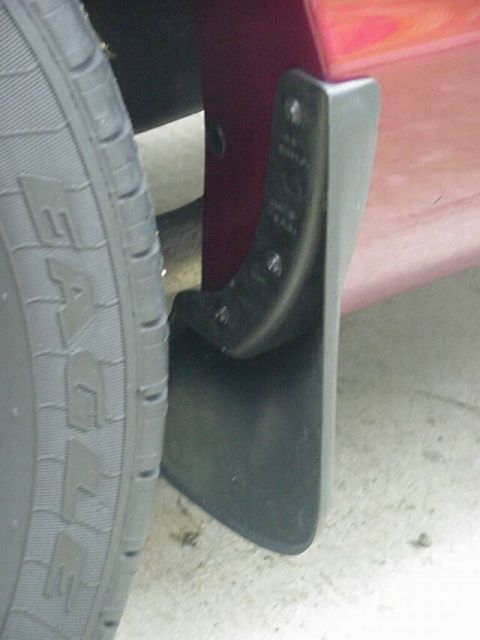 2002 Ford Crown Victoria - Close-up view of a rear mud flap and tire on a red vehicle.