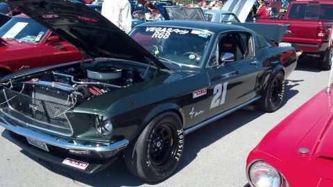 2007 Ford Mustang - A vintage Ford Mustang, modified for racing, is displayed with its hood up at an outdoor car show.