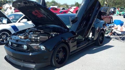 2007 Ford Mustang - A black Ford Mustang with its hood and doors open at a car show, with other vehicles in the background.