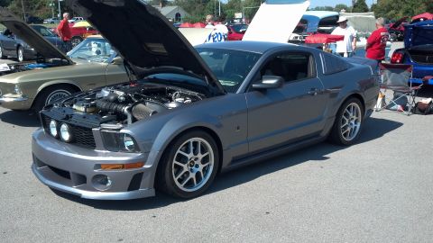 2007 Ford Mustang - A gray 2007 Ford Mustang is displayed with its hood open at a car show, revealing the engine compartment.