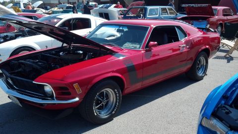 2007 Ford Mustang - A red classic Mustang is displayed with its hood open at an outdoor car show, alongside other vehicles.