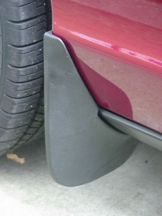 Black mud flap behind rear tire of a dark red sedan