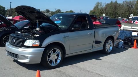 2007 Ford Mustang - This two-tone 1999 Ford F-150 SVT Lightning pickup truck is displayed at a car show with its hood open.