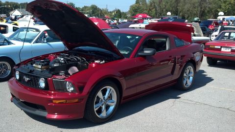 2007 Ford Mustang - A red Ford Mustang is displayed with its hood and trunk open at an outdoor car show.