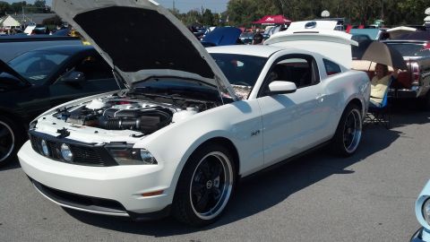2007 Ford Mustang - A white Ford Mustang is displayed with its hood open at an outdoor car show.