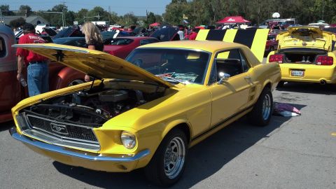 2007 Ford Mustang - A bright yellow 1967 Ford Mustang coupe is displayed with its hood open at a car show, with another yellow Mustang visible in the backgroun…