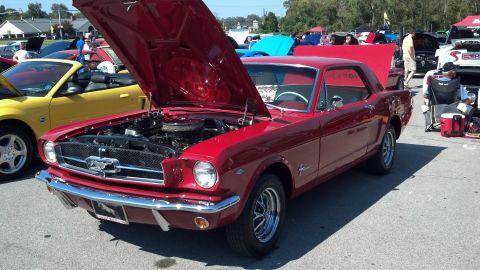 2007 Ford Mustang - A classic red Ford Mustang is displayed with its hood open at an outdoor car show, alongside other vehicles.
