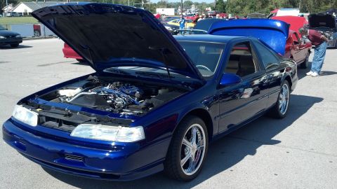2007 Ford Mustang - A blue 1997 Ford Thunderbird is displayed with its hood open at a car show, revealing the engine bay.