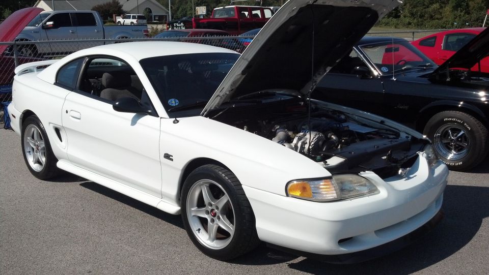 White 1996 Ford Mustang coupe with hood open, parked next to a black car