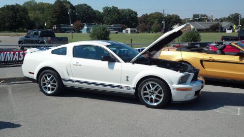 2007 Ford Mustang - White 2007 Ford Mustang GT 500 with hood open, parked next to a yellow convertible.