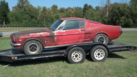 2007 Ford Mustang - A classic red Ford Mustang is loaded onto a trailer, appearing to be in need of restoration.