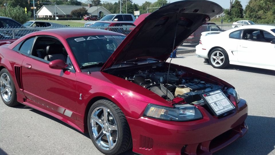 Red 2007 Ford Mustang coupe with hood open, showing engine and a placard