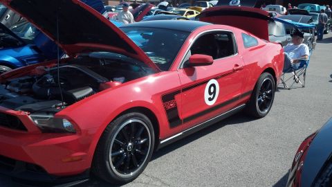 2007 Ford Mustang - A red Ford Mustang Boss 302 is displayed at a car show with its hood open.