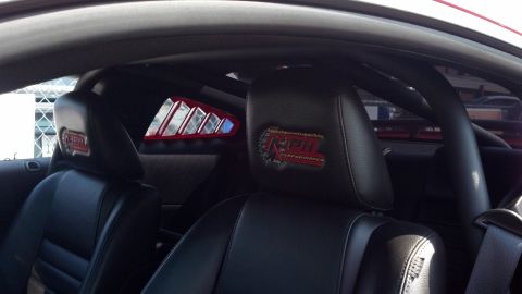 2007 Ford Mustang - The interior of a car features racing seats, a roll cage, and a distinctive logo on the headrests.