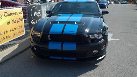2007 Ford Mustang - A black Ford Mustang Shelby GT500 with blue racing stripes is parked outside.
