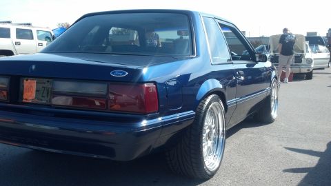 2007 Ford Mustang - A blue coupe with custom wheels is parked at an outdoor event with other vehicles and people present.