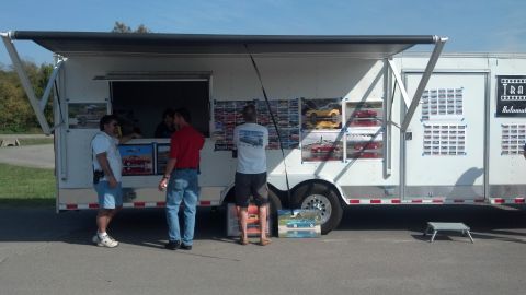 2007 Ford Mustang - A trailer displays numerous model cars in windows, with several people gathered around.