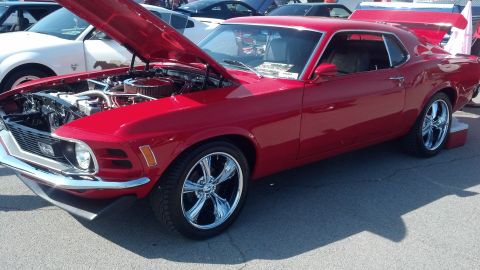 2007 Ford Mustang - This classic red Ford Mustang features a prominent rear spoiler and its hood is open, revealing the engine compartment.