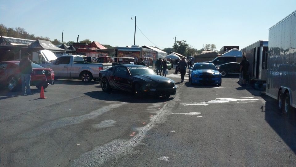 Black 2007 Ford Mustang parked at an outdoor event with a blue Mustang and a pickup truck nearby