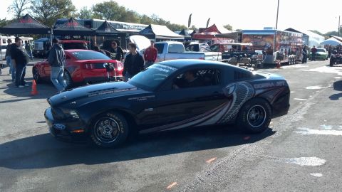 2007 Ford Mustang - A black Ford Mustang modified for drag racing is parked at an outdoor event with tents and other vehicles visible.