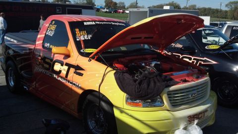 2007 Ford Mustang - A custom Ford F-150 Lightning pickup truck with vibrant graphics and an open hood is parked next to another vehicle.