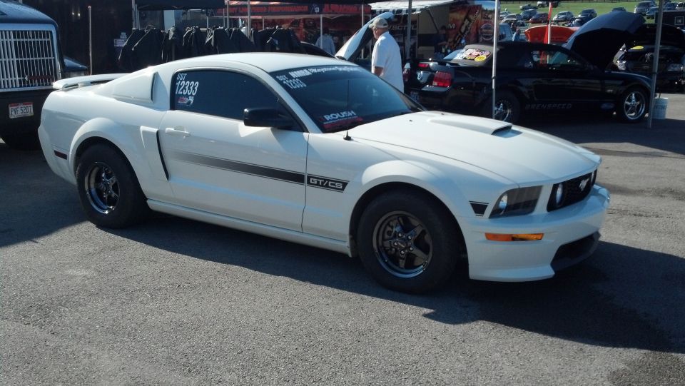 White Ford Mustang GT/CS with racing slicks and a hood scoop, parked outdoors