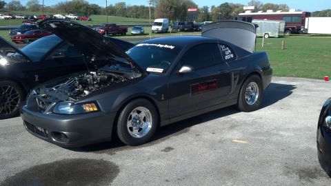 2007 Ford Mustang - A dark gray 2007 Ford Mustang is parked with its hood and trunk open, displaying racing decals on the rear window.
