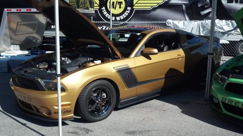 2007 Ford Mustang - A gold Ford Mustang is displayed with its hood up, next to a green Mustang at an outdoor event.