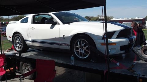 2007 Ford Mustang - White Ford Mustang GT500 with blue racing stripes is loaded onto a car hauler.