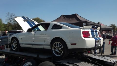 2007 Ford Mustang - A white 2007 Ford Mustang Shelby GT500 is loaded onto a trailer with its hood open.