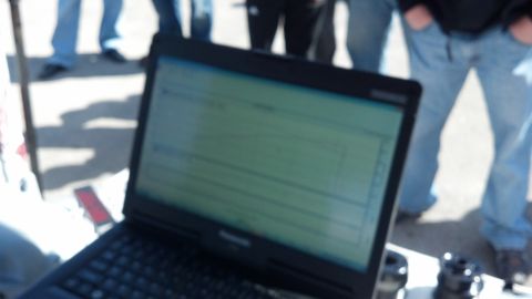 2007 Ford Mustang - A laptop is open and displaying information, with several people standing in the background.