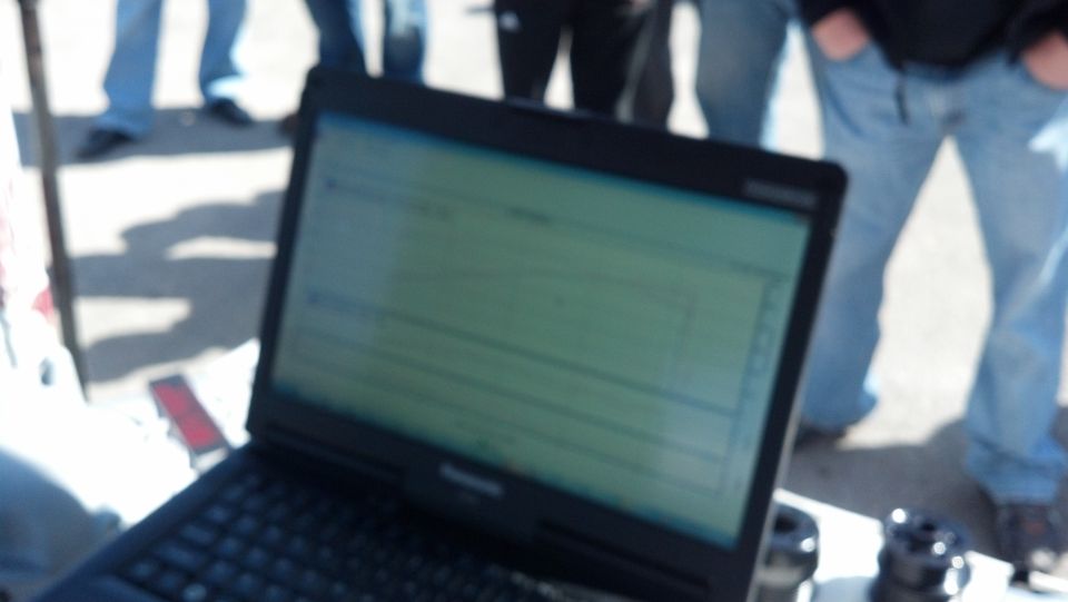 laptop screen showing data with people standing around