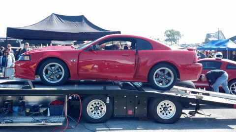 2007 Ford Mustang - Two red Ford Mustangs are seen at an event, one loaded onto a car hauler.