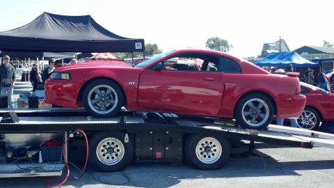 2007 Ford Mustang - A red Ford Mustang GT is being transported on a car hauler, with another similar vehicle visible in the background.
