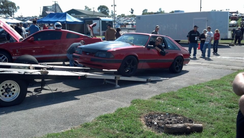 Red coupe with black hood being loaded onto a trailer