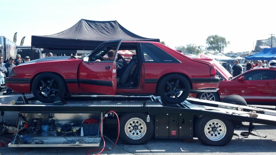 Red fox body Mustang coupe on a car hauler, another red Mustang visible behind it