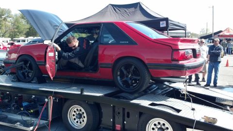 2007 Ford Mustang - A red fox body Mustang is being worked on while loaded onto a trailer at an outdoor event.