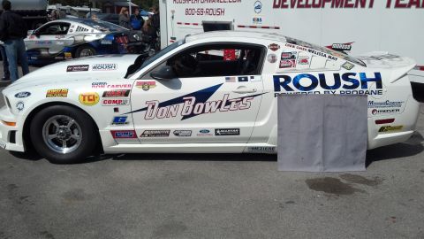 2007 Ford Mustang - A 2007 Ford Mustang race car, branded with ROUSH and Don Bowles livery, is seen from the side, with another Mustang in the background.
