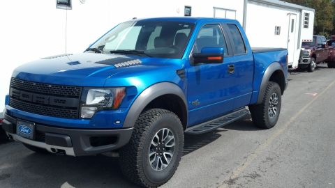 2007 Ford Mustang - A blue Ford F-150 SVT Raptor pickup truck is parked in front of a white trailer.