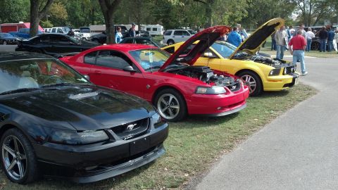 2007 Ford Mustang - Several Ford Mustangs are displayed with their hoods open at an outdoor event.