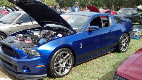 2007 Ford Mustang - A blue Ford Mustang Shelby GT500 is parked on grass with its hood open, revealing the engine compartment.