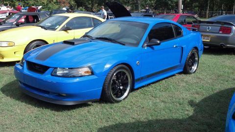 2007 Ford Mustang - A blue Ford Mustang is parked on grass with other vehicles around it.