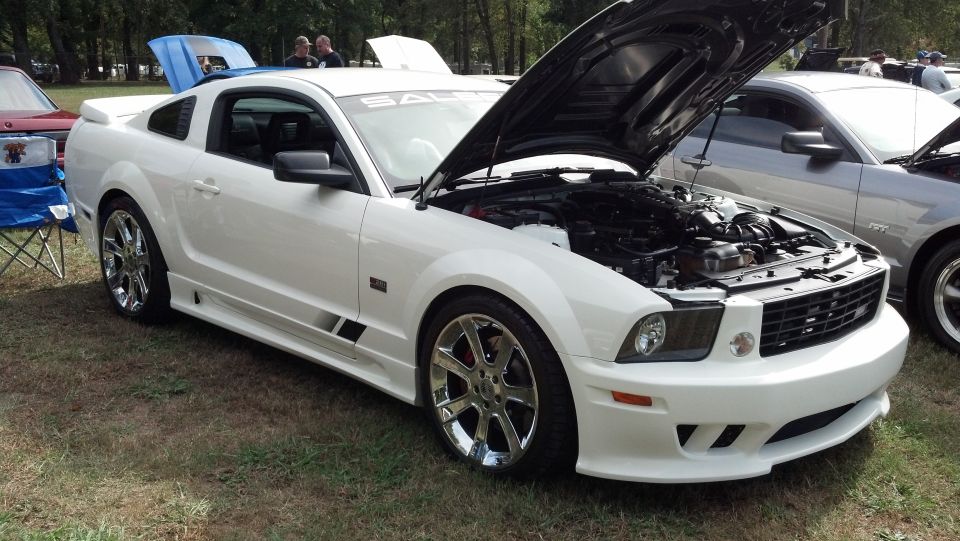 White Saleen Mustang with hood open, parked on grass next to another car